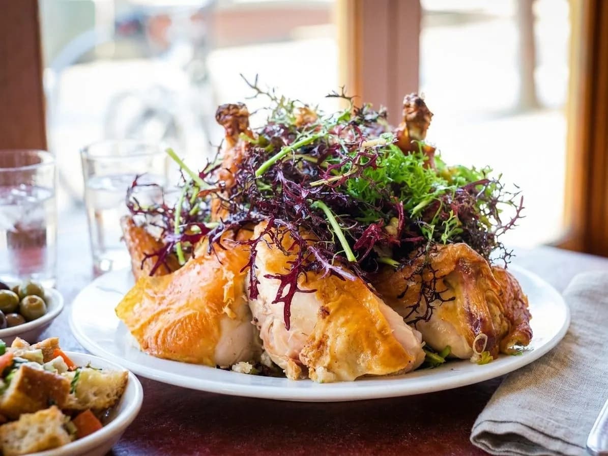 A roast chicken dinner and side plates on a table at Zuni Café in San Francisco