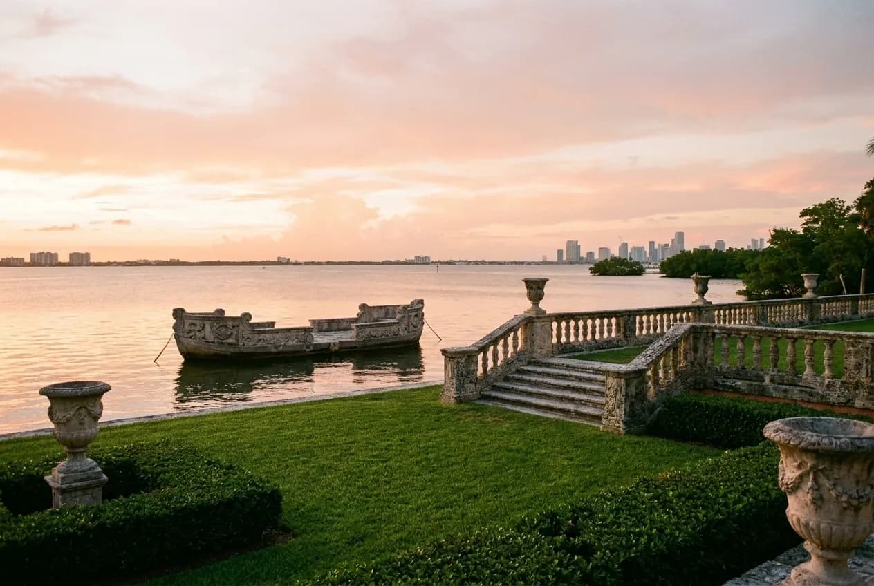 Formal garden overlooks Biscayne Bay at sunset with stone balustrade and decorative barge in Coconut Grove.