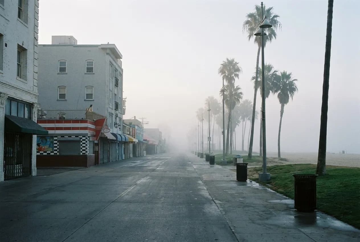 Early morning marine layer hanging over a Los Angeles coastal boardwalk with empty bike path