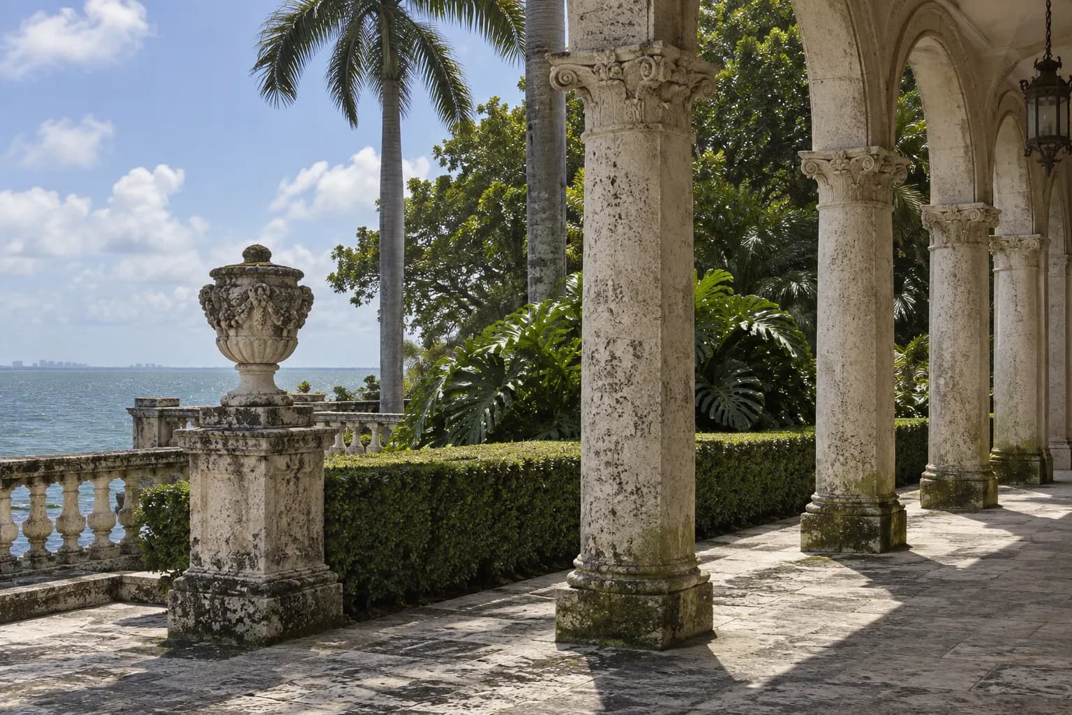 A shaded coral-stone courtyard walkway in a historic Miami estate with tropical planting