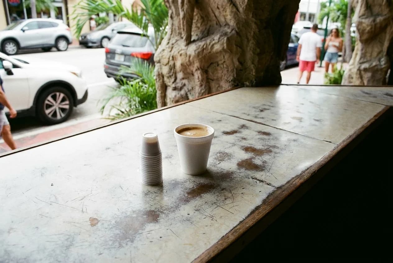 Cuban colada coffee in styrofoam cup with plastic thimbles on ventanita counter in Little Havana