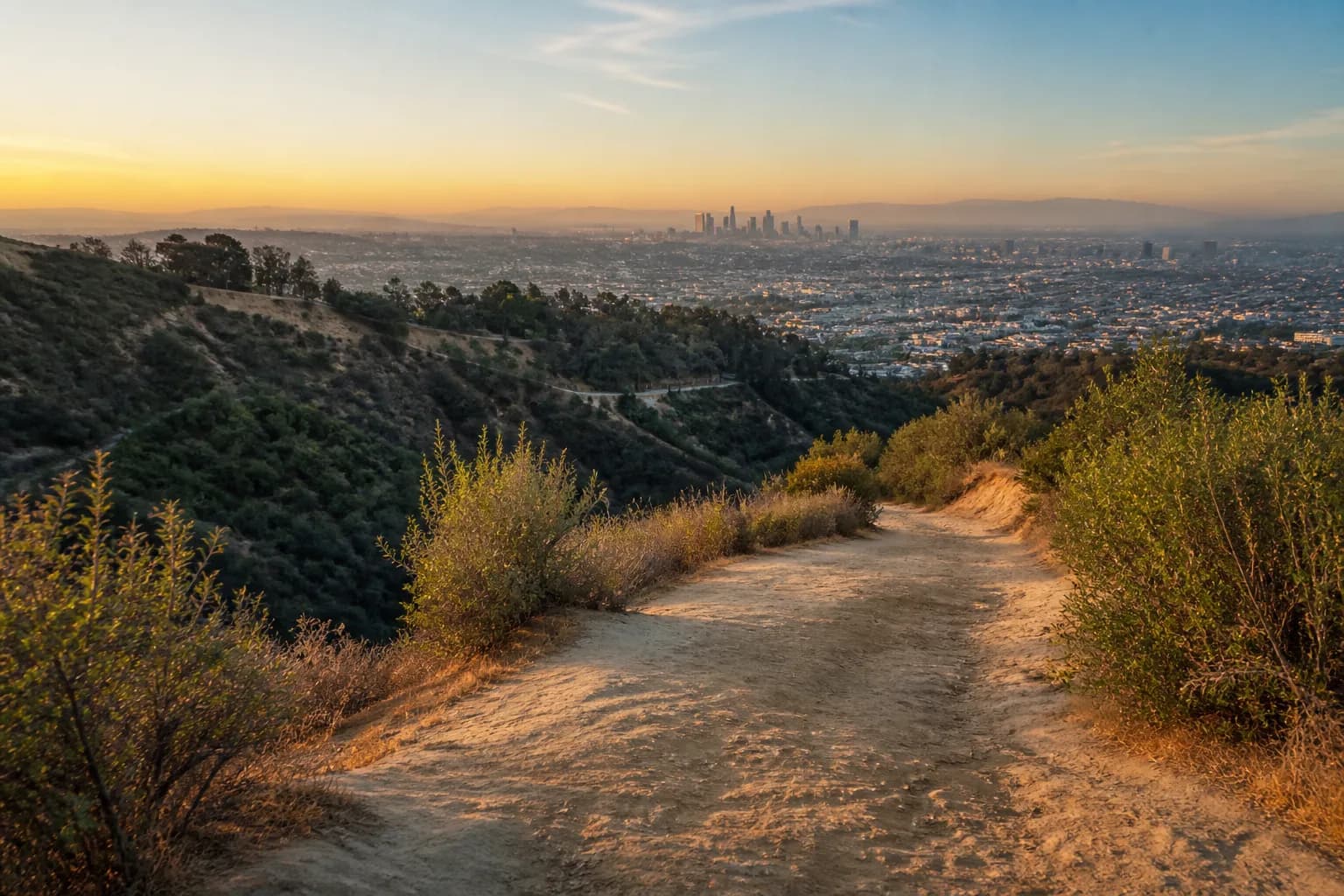 Early morning hiking trail rising toward Griffith Observatory with the Los Angeles basin in soft light.