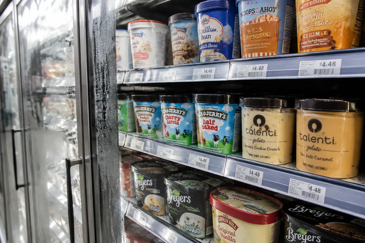 Freezer aisle shelves stocked with colorful ice cream pints under fluorescent light