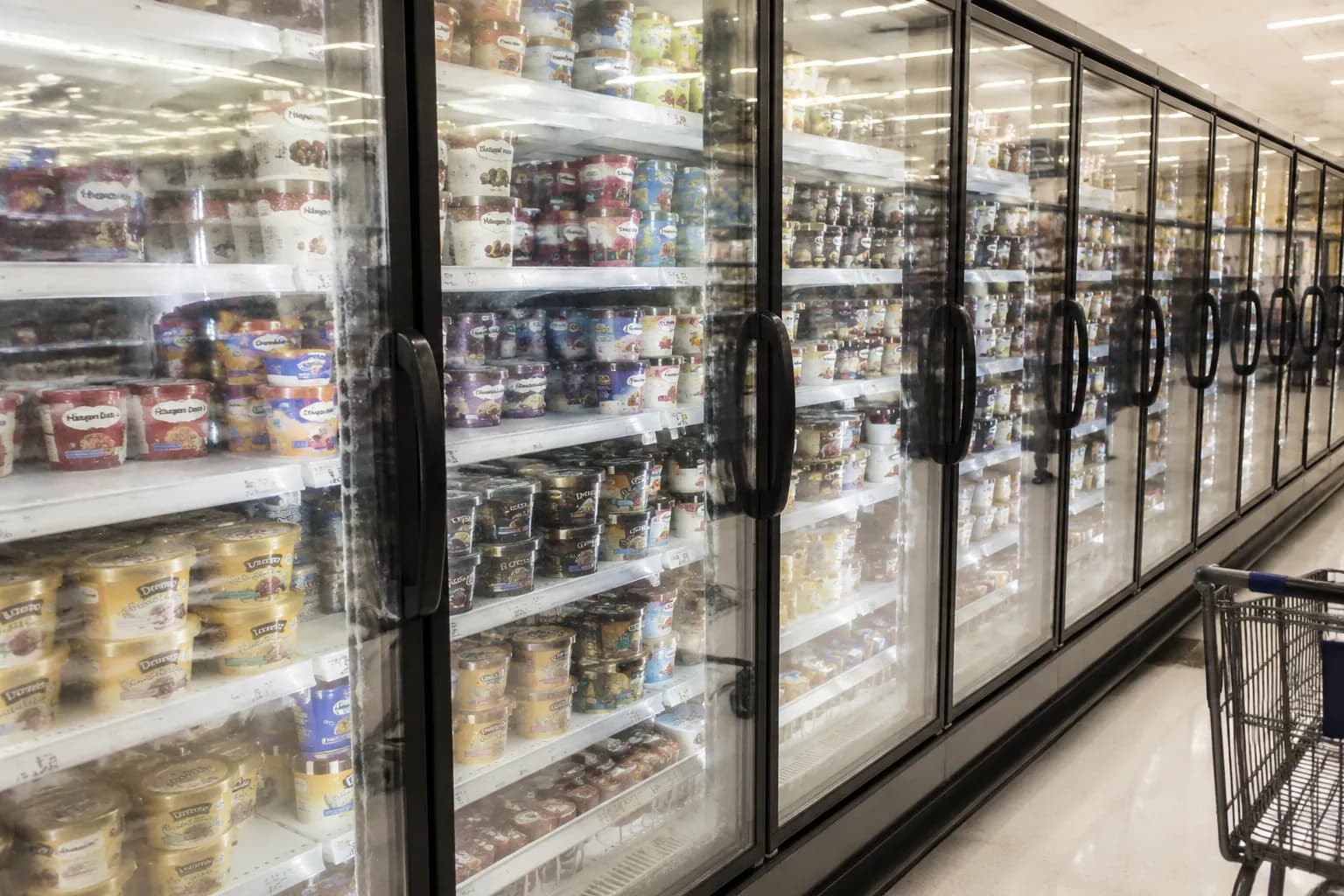 Freezer aisle in a New York City Whole Foods with rows of ice cream pints behind glass doors