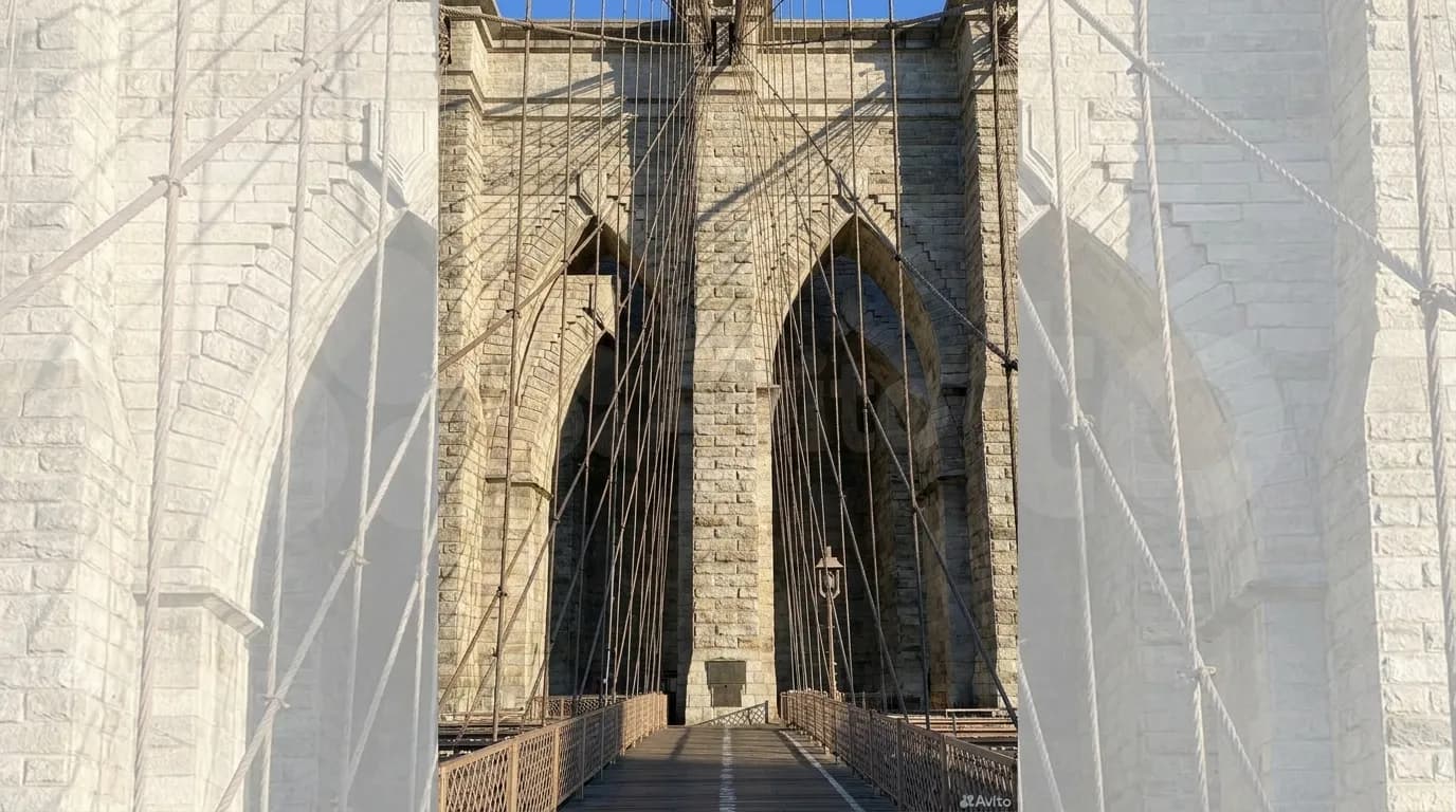 Gothic stone arch of Brooklyn Bridge tower with steel suspension cables radiating upward