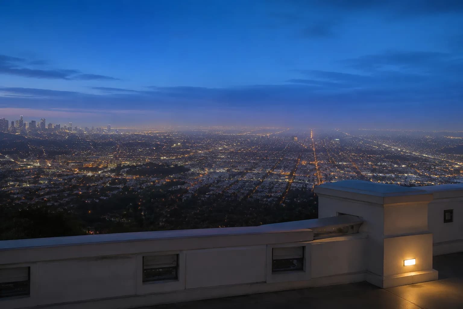 Los Angeles city basin at dusk viewed from Griffith Observatory terrace with downtown skyline visible