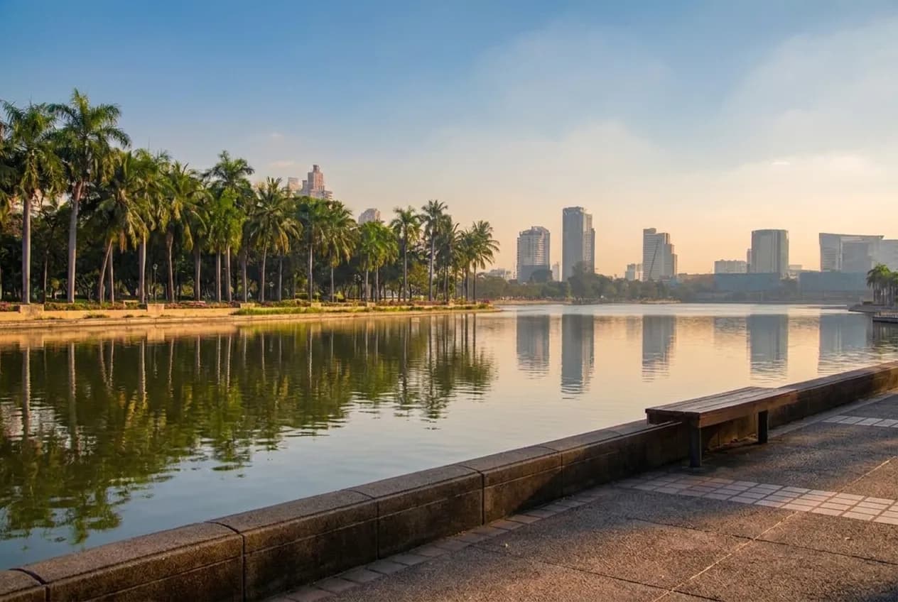 A palm-lined park lake with the downtown Los Angeles skyline behind it in afternoon light