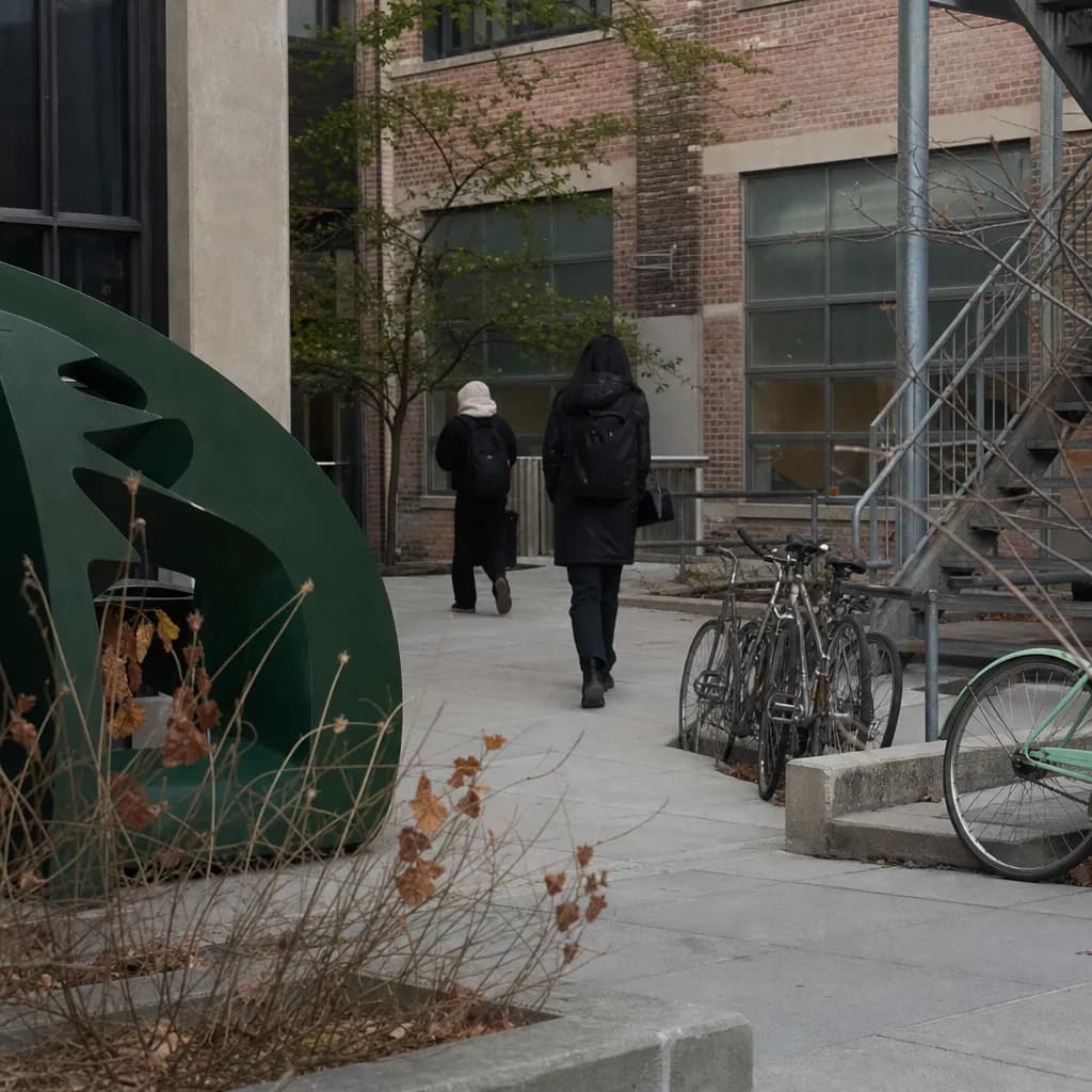 A Brooklyn art-school courtyard with brick, metal, and partial student silhouettes