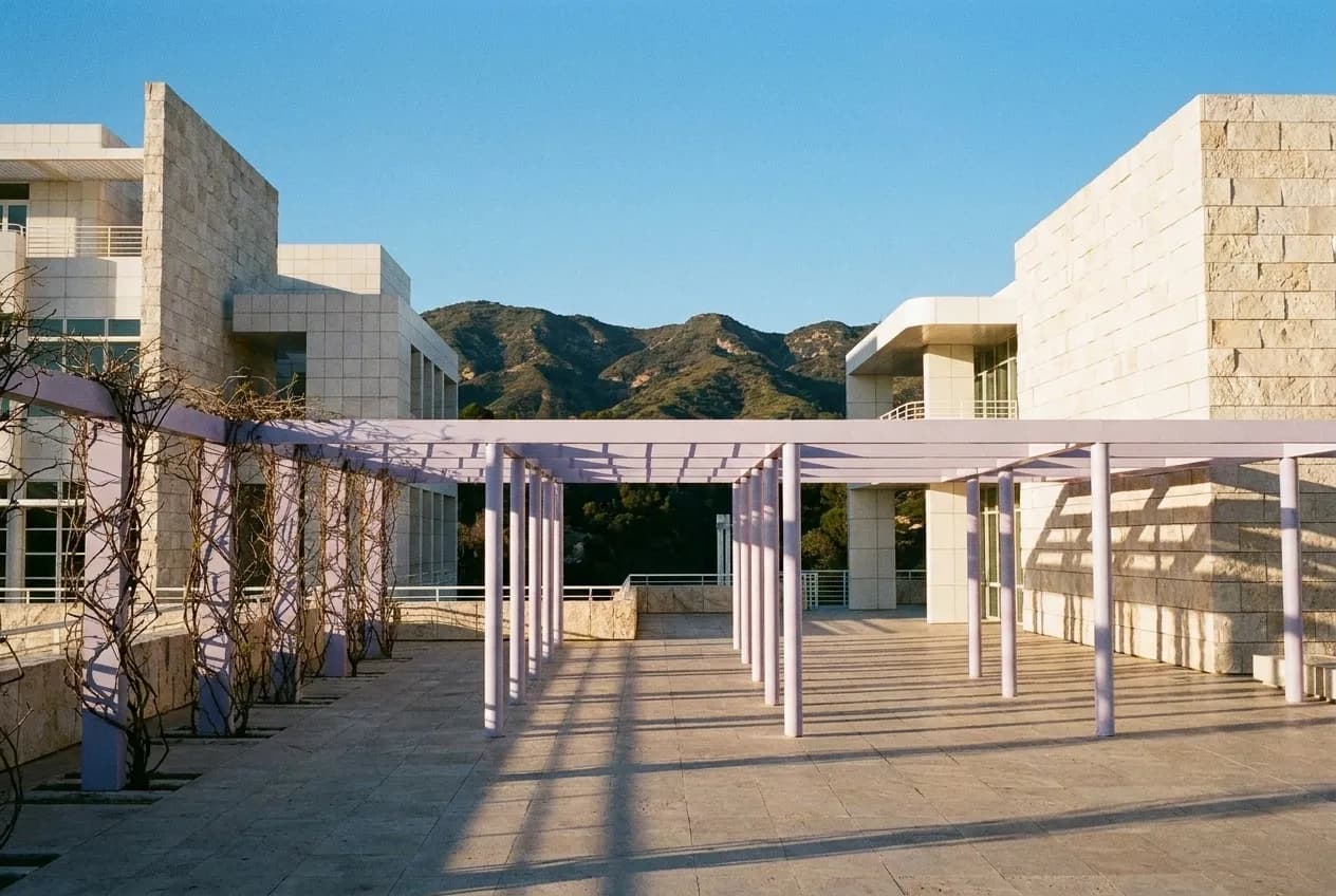 White travertine pavilions of the Getty Center in afternoon sunlight with Santa Monica Mountains in the background.