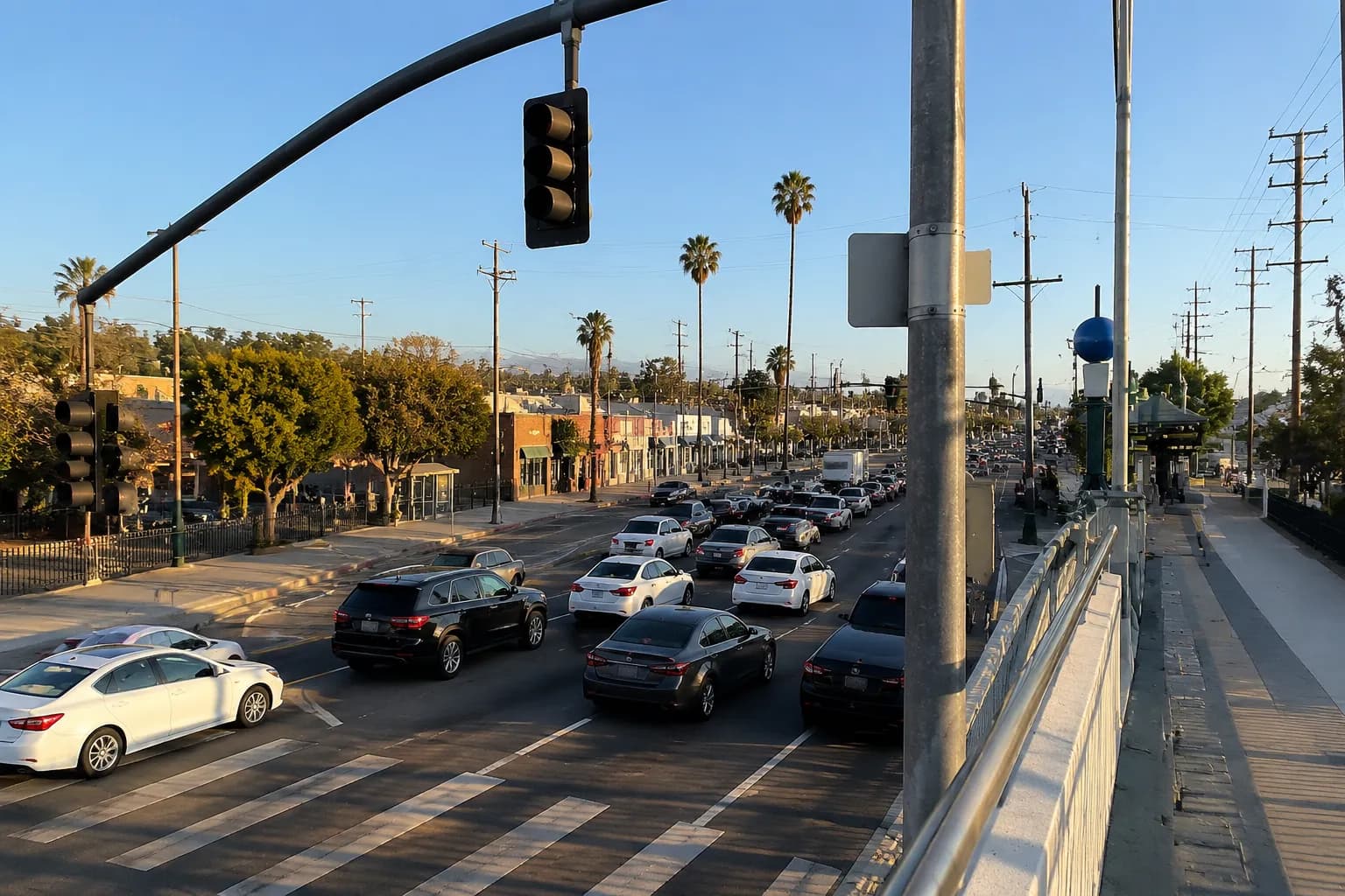 Morning traffic on Figueroa Street in Los Angeles with palm trees and intersection signals under hazy blue sky