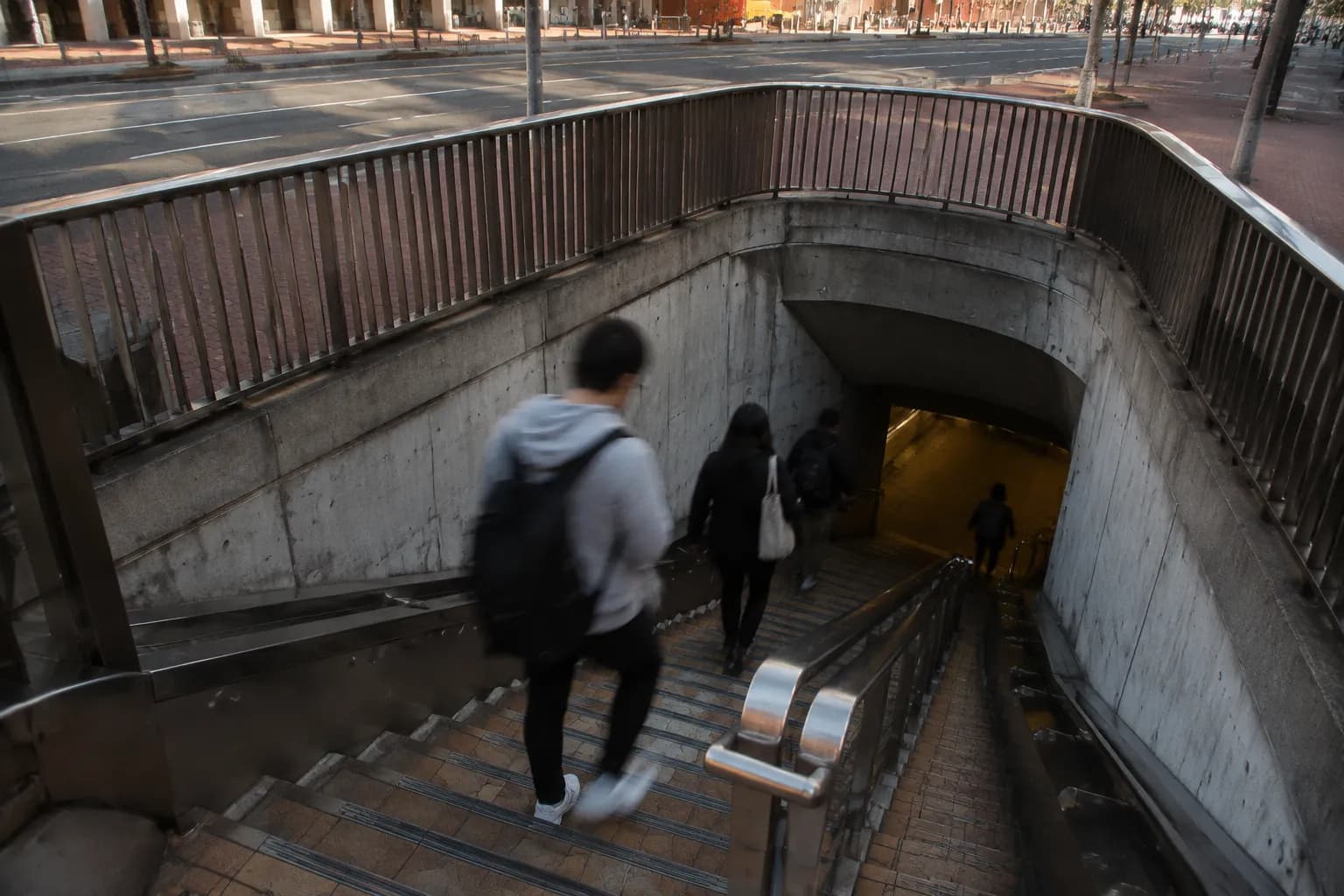 Stairs leading down into Embarcadero BART station entrance with commuters in motion