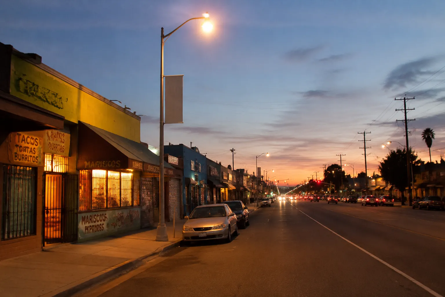 Cesar Chavez Avenue in Boyle Heights at dusk with streetlights and storefronts