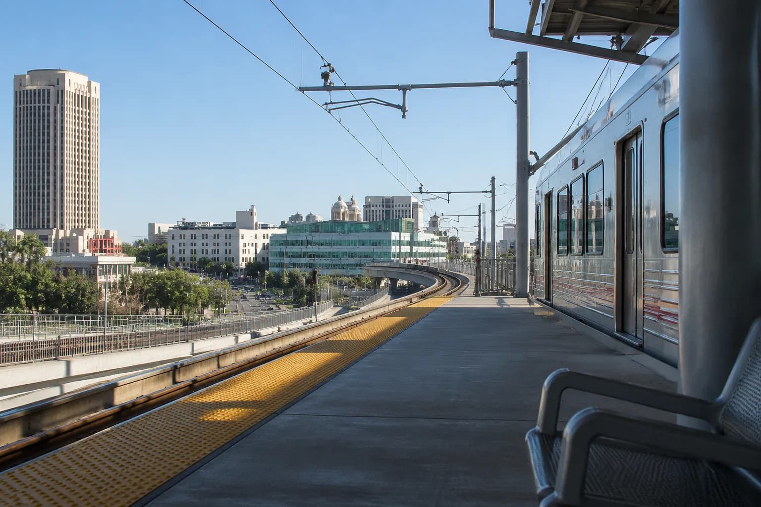 Gold Line platform at Chinatown station in Los Angeles with train and downtown skyline visible in background