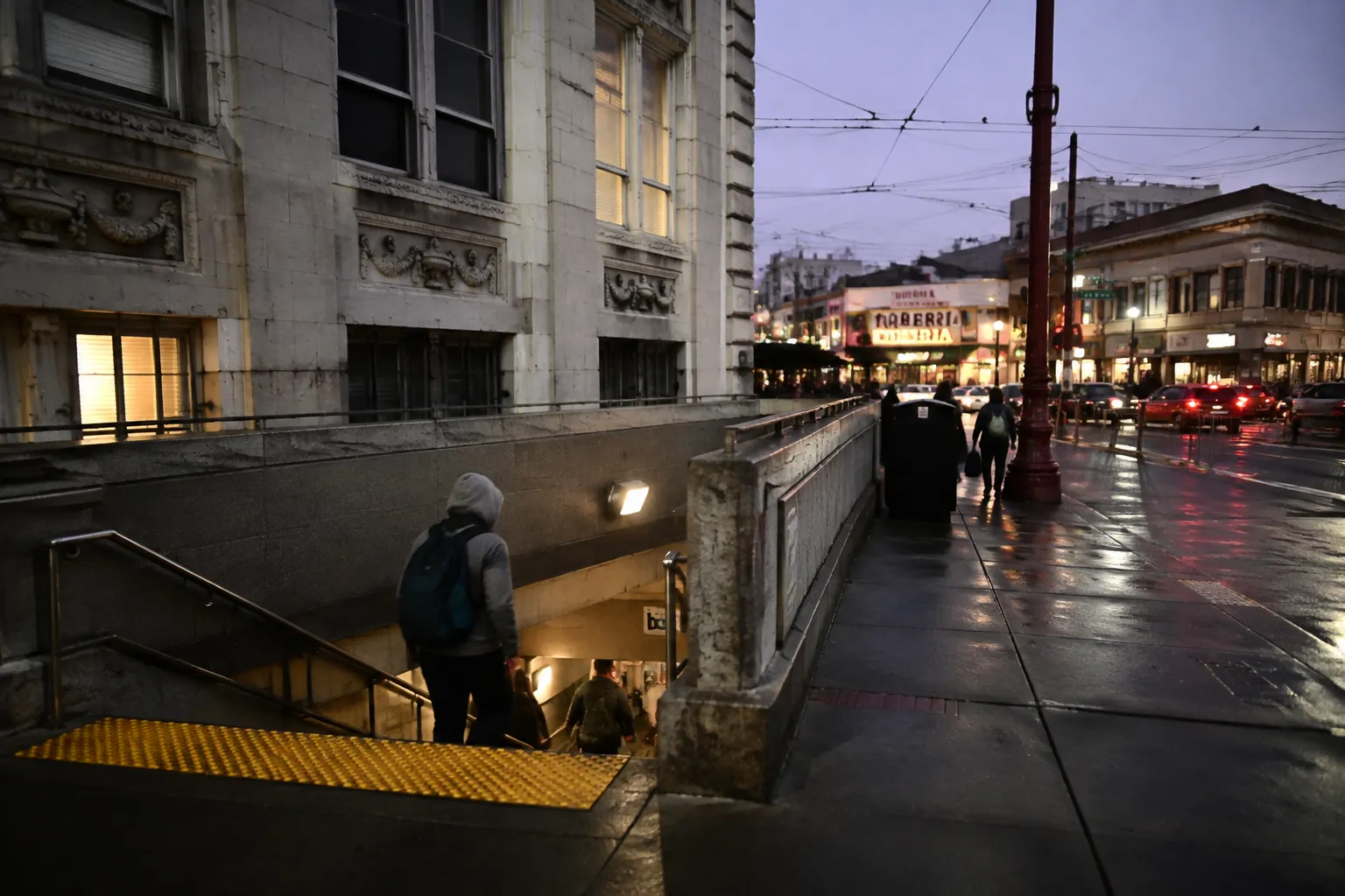 BART station entrance on Mission Street at twilight with commuters and lit storefronts in San Francisco