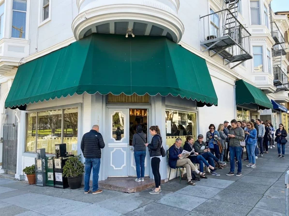 Weekend line outside a North Beach breakfast spot near a city square