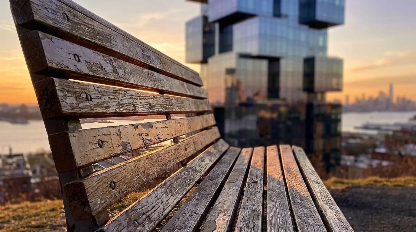Sunset Park hilltop overlook with wooden benches facing west toward New York Harbor and distant Manhattan skyline