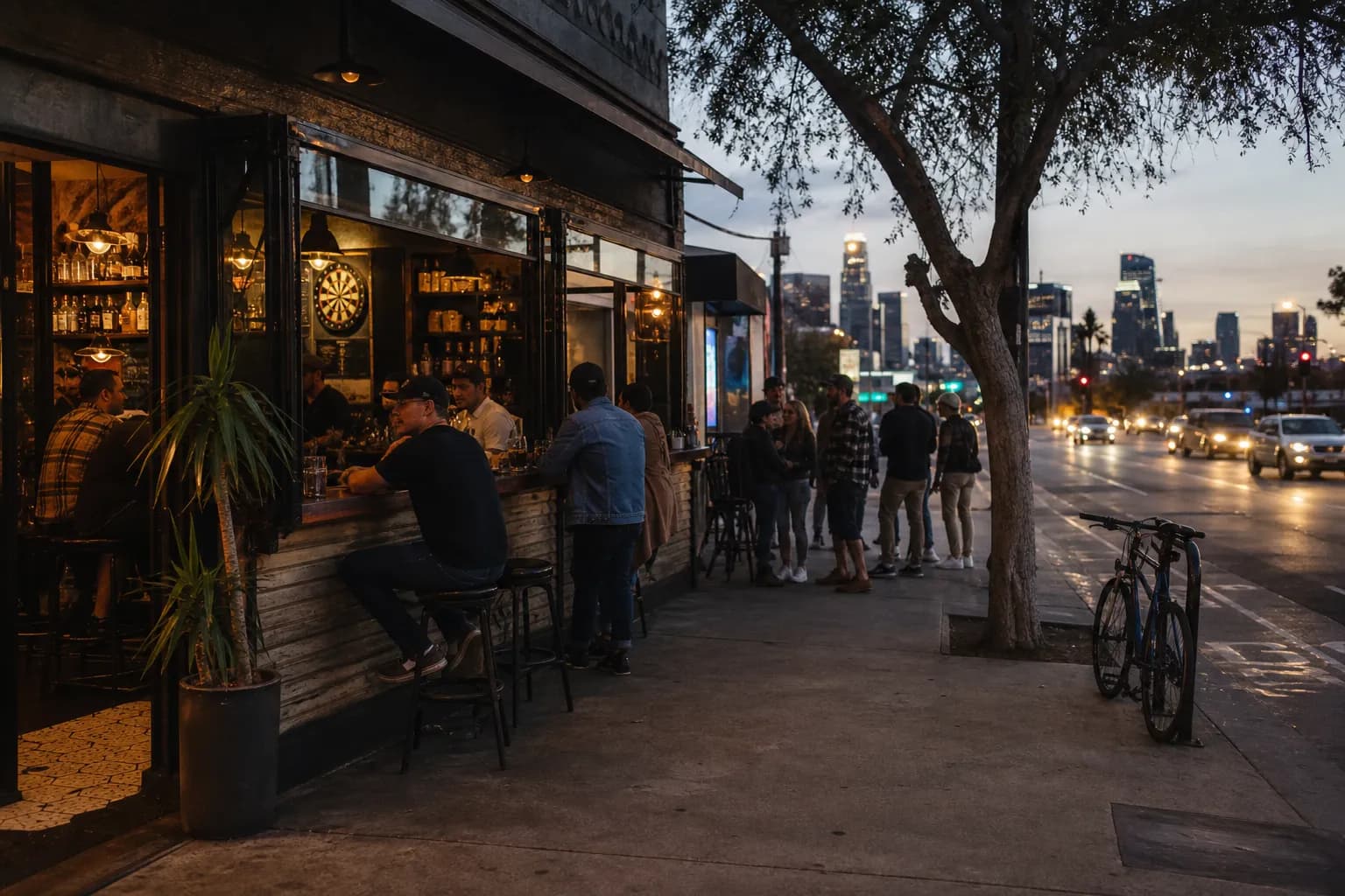 A lively Los Angeles neighborhood bar exterior glowing at dusk near a busy sidewalk