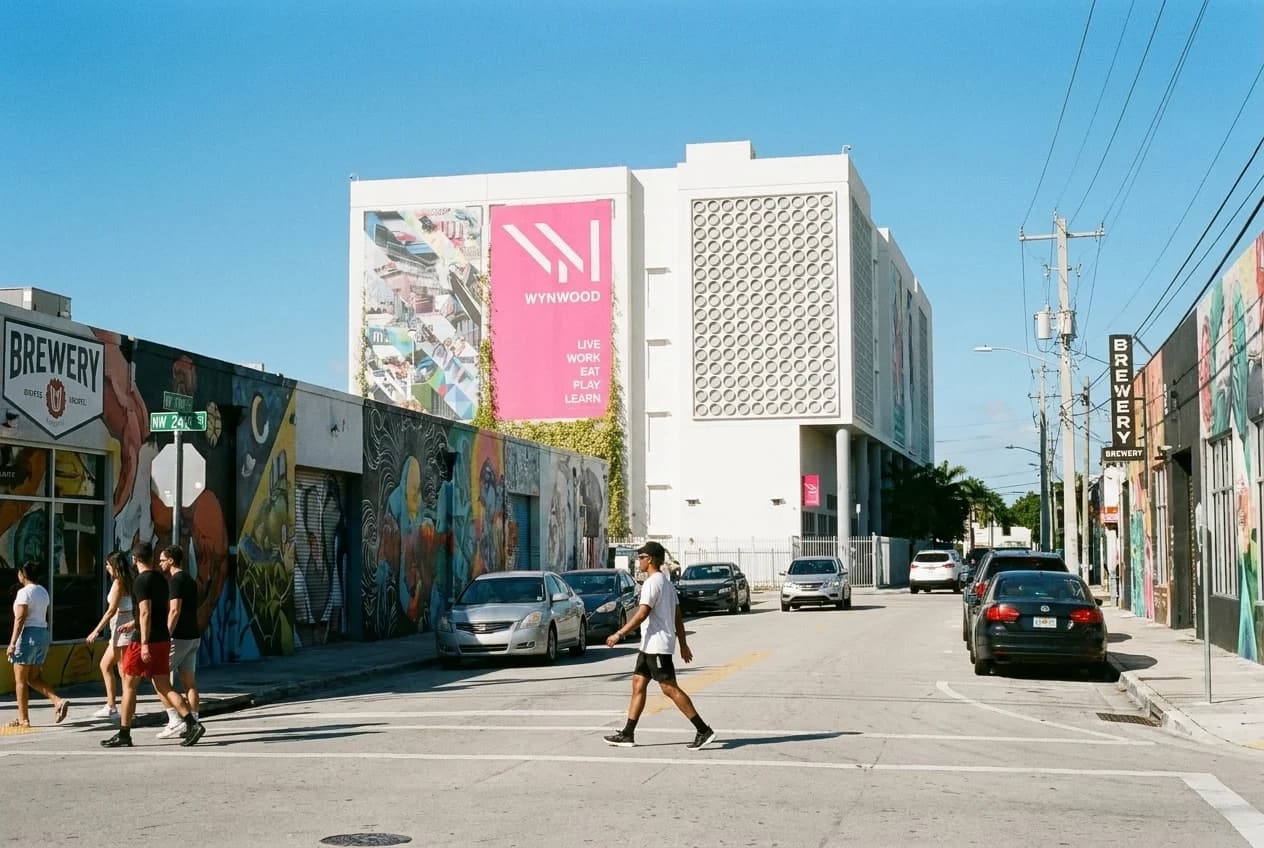 Pedestrian crossing NW 24th Street in Wynwood with brewery signage and mural-covered warehouses