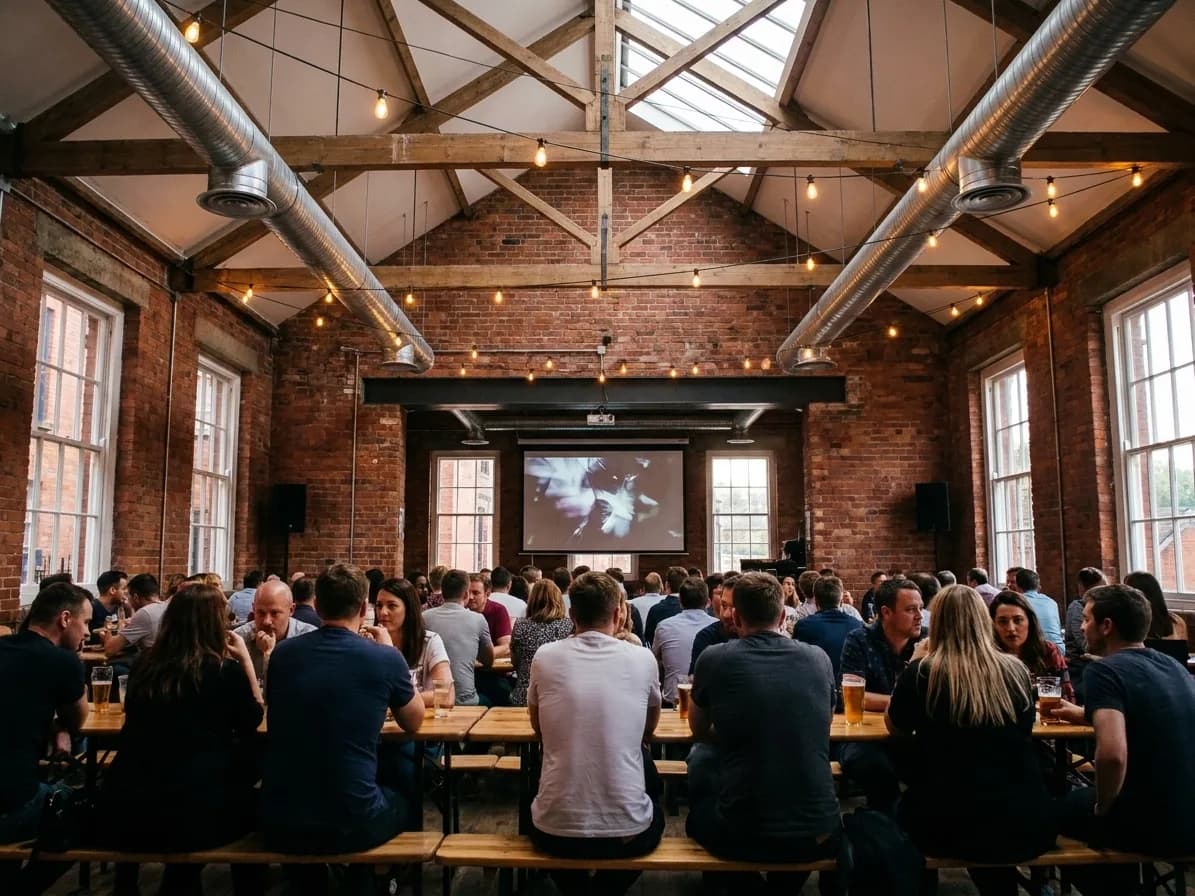 A converted warehouse bar with a large screen and communal tables