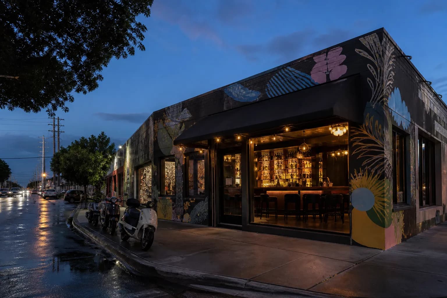 Mural-lined Wynwood street at dusk with glowing bar windows and pedestrians