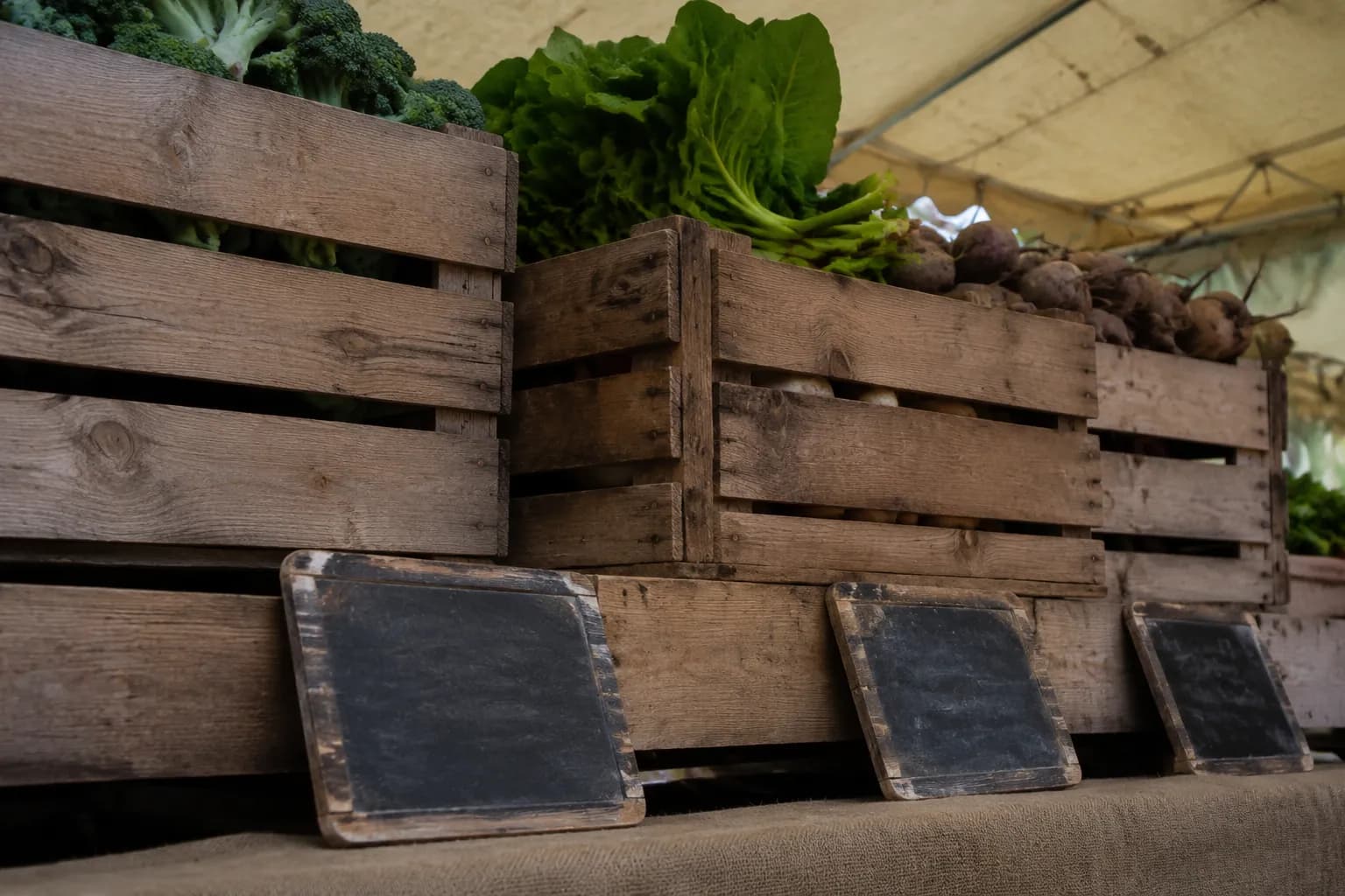 Wooden produce crates and handwritten price signs at a Los Angeles farmers market stall